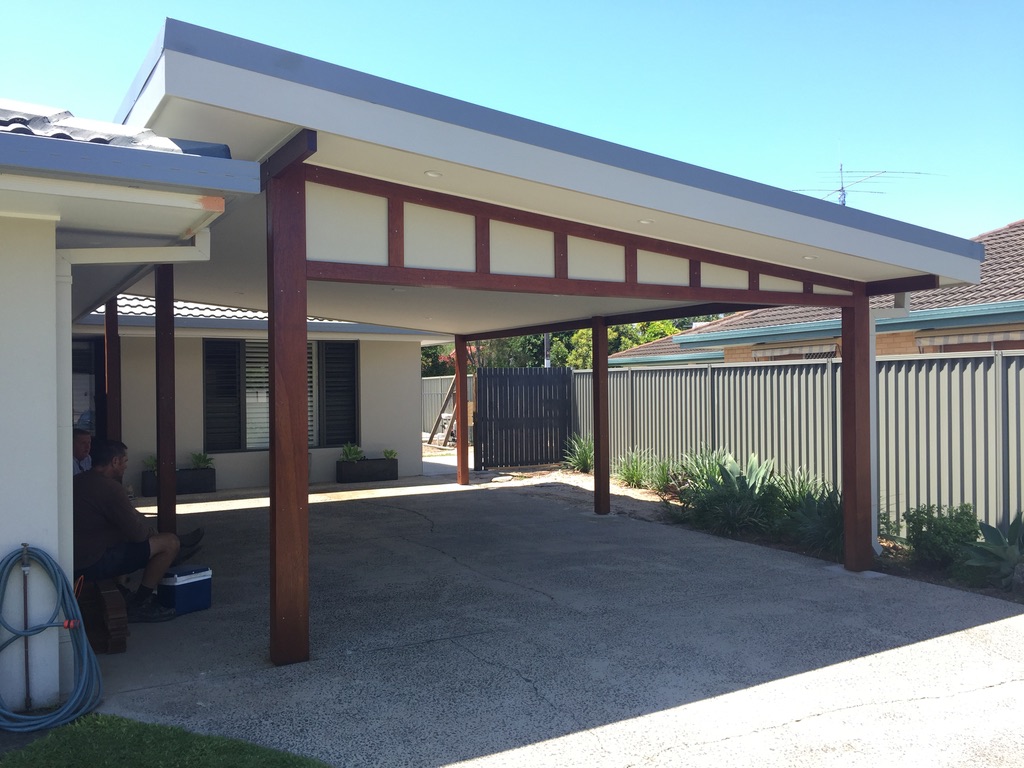 Flat-roof carport with stained hardwood posts and a slatted timber feature panel