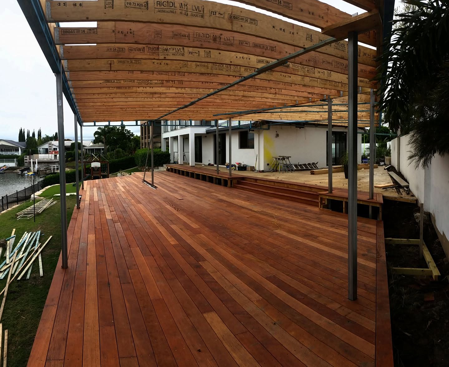 Large hardwood deck over a Gold Coast canal with a steel-framed pergola overhead