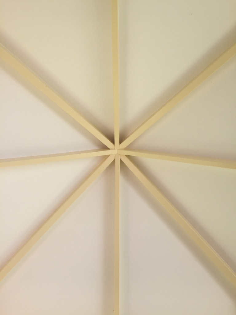 Underside of a hipped pavilion roof with radiating painted timber beams