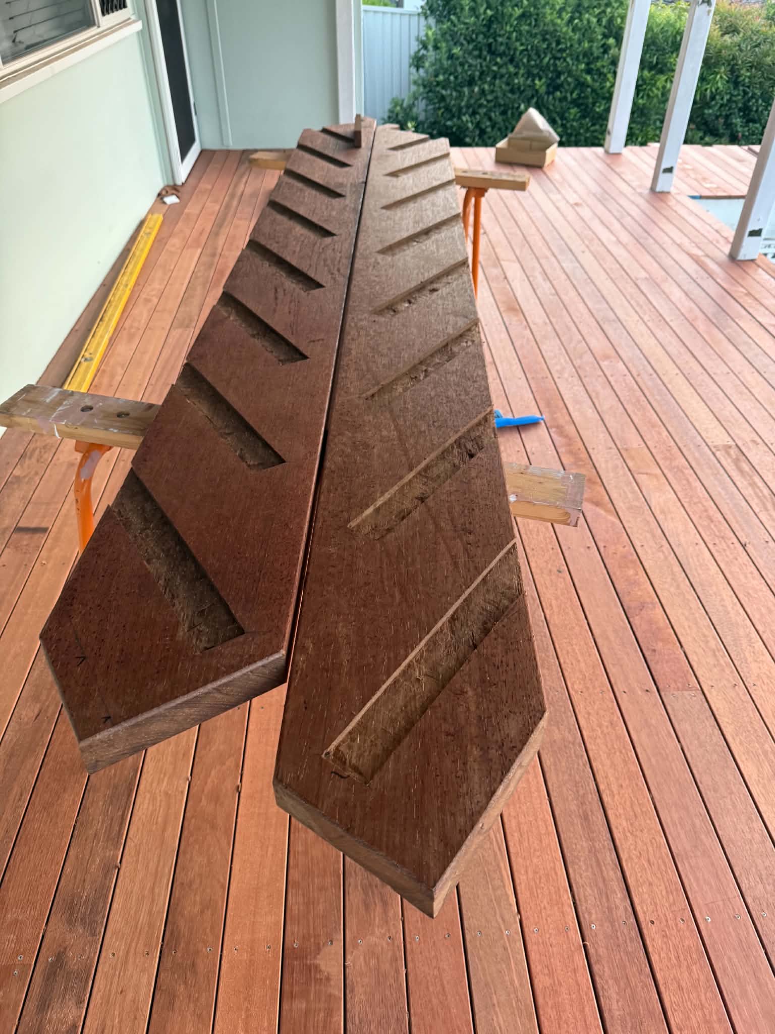 A pair of hand-cut hardwood stair stringers laid out on a finished hardwood deck